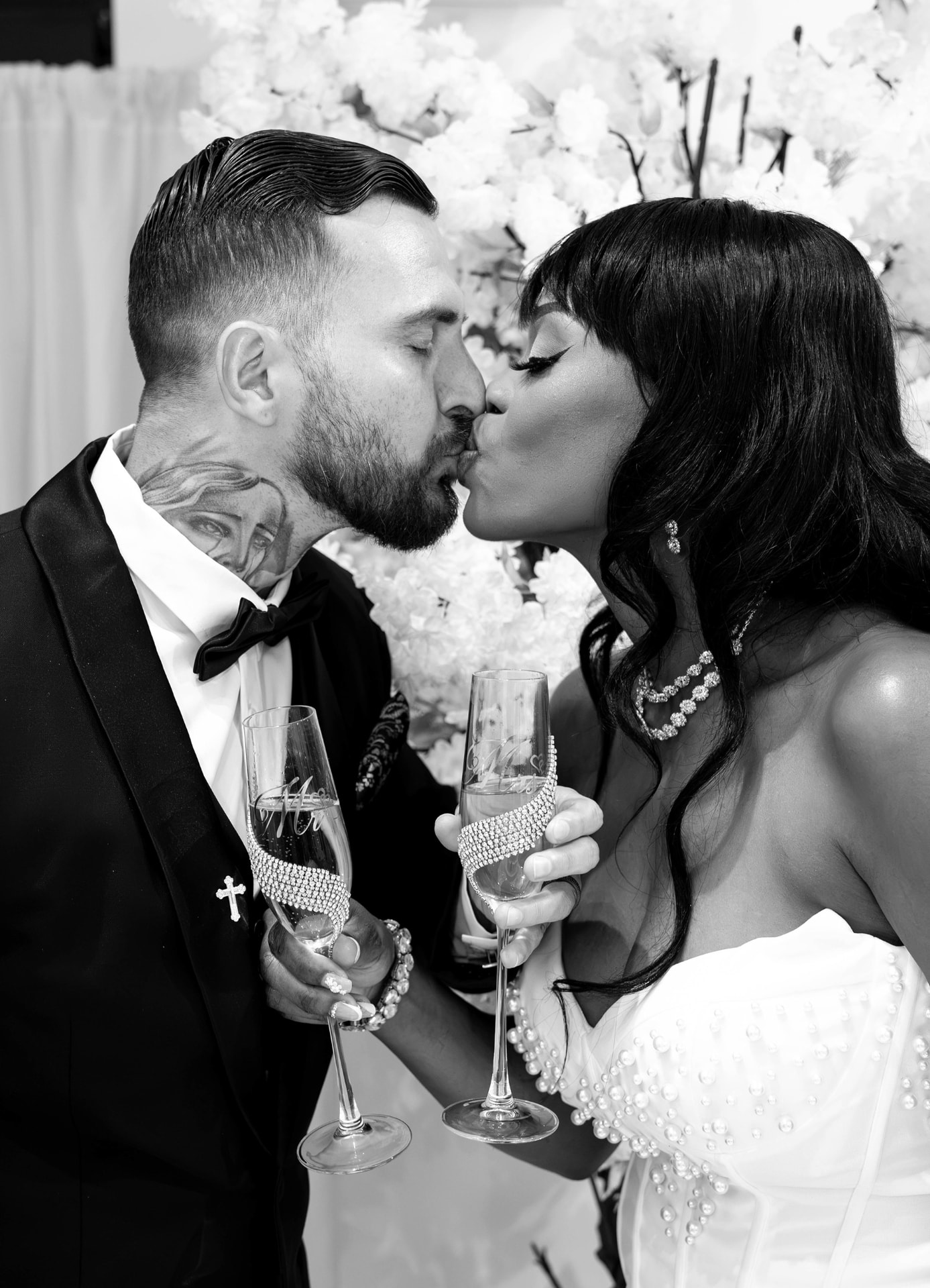 Nicholas and Lourdie sharing a kiss with champagne flutes at their wedding reception